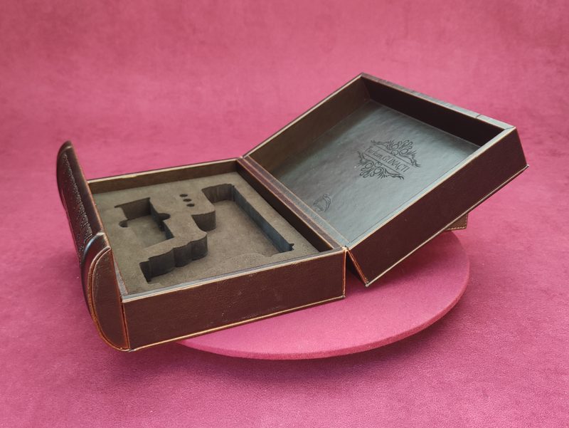 Open brown book-form box showing custom laser-cut interior