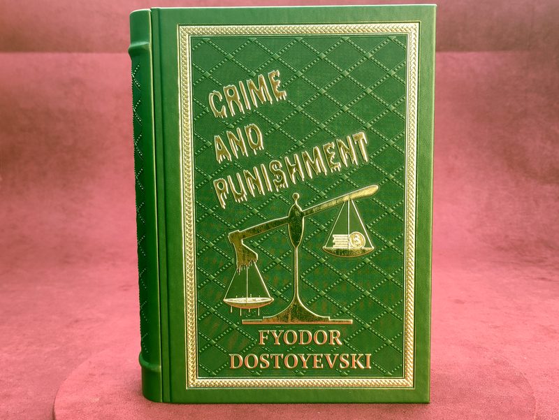 Front board of the green Crime and Punishment box with gold-foiled scales of justice