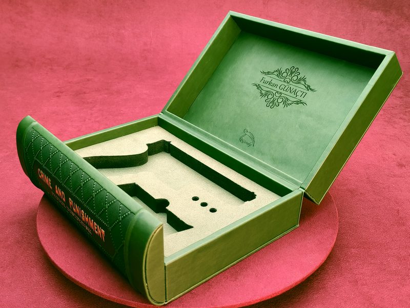 Open green book-form box showing custom laser-cut interior