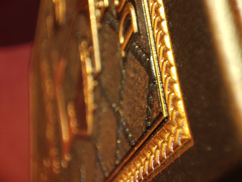 Macro of gold foil floral scrollwork on leather
