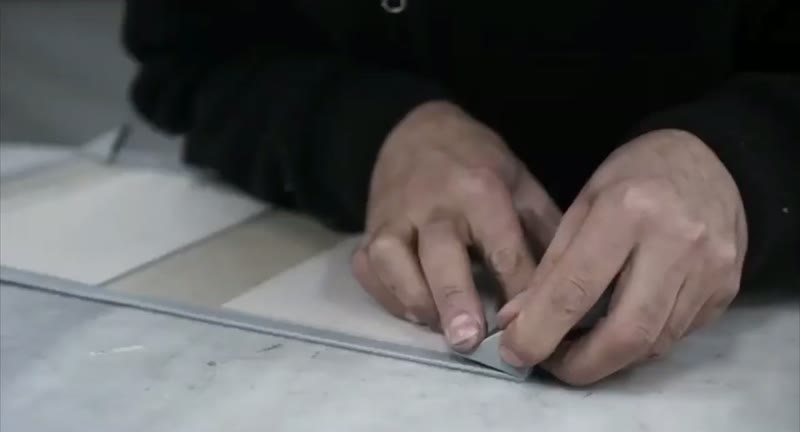 Hands smoothing leather over a cover board